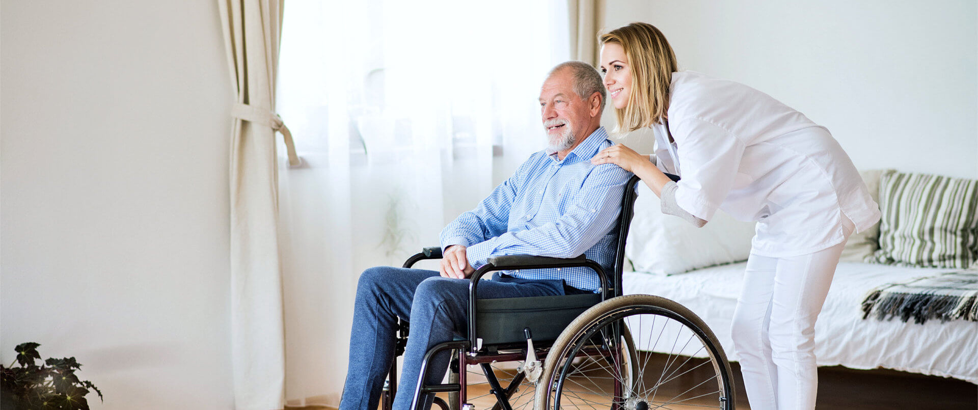 caregiver and senior man on wheel chair looking outside