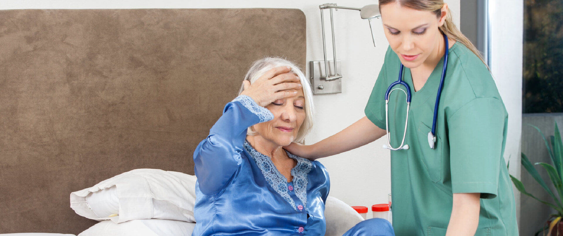 caregiver with stethoscope assisting senior woman