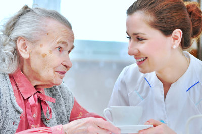caregiver and senior woman smiling while holding a cup