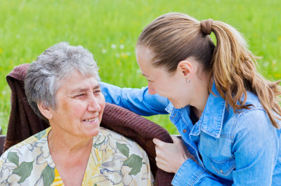 senior woman smiling while caregiver putting towel around her back