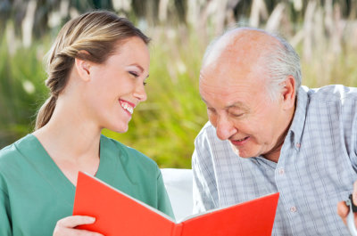 caregiver and senior man smiling while reading